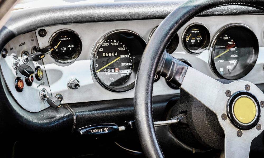 Inside of a racing car showing steering wheel and dashboard.