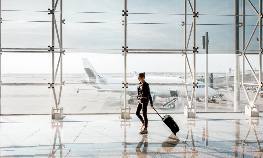 A lady passenger wheeling her suitcase through an airport terminal.
