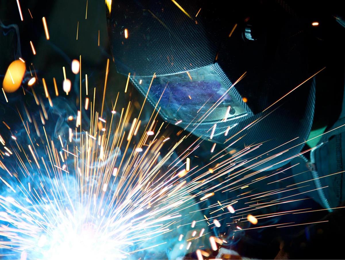A welder using a welder with sparks flying. Stylised image with dark background to emphasize the sparks in the foreground.